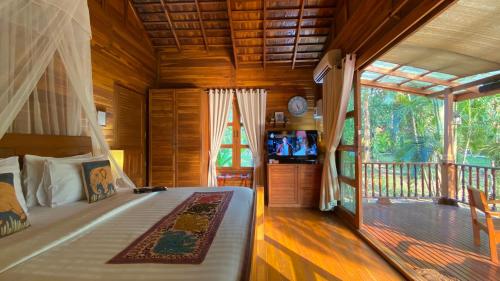 a bedroom with a bed and a balcony with a television at Nan Seasons Boutique Resort in Nan