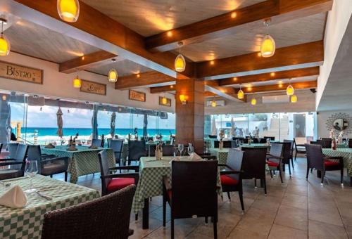 a restaurant with tables and chairs and the ocean at The Oceanfront by Casa Paraiso in Cancún