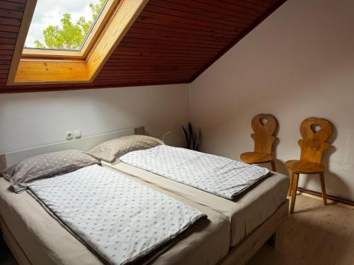 a bedroom with a bed with a window and two chairs at Rooms Apartma Cerknica in Cerknica