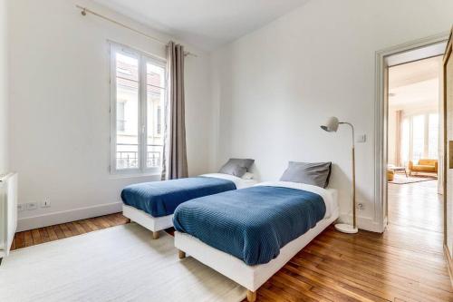 - 2 lits dans une chambre dotée de murs blancs et de parquet dans l'établissement Elegant 2-bedroom appartment in Saint-Denis, à Saint-Denis