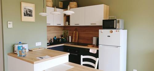 a kitchen with a white refrigerator and a table at Gîte Casa' Nahi. Barfleur in Barfleur