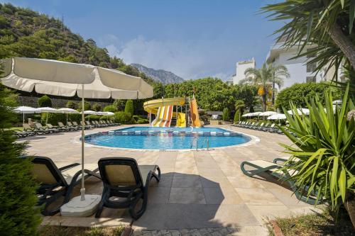 a swimming pool with chairs and a slide at Sunland Resort Beldibi in Beldibi