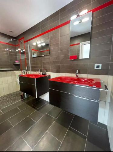 La salle de bains est pourvue de 2 lavabos rouges et d'un miroir. dans l'établissement Summer House Vip, à Saint-Hilaire-de-Riez