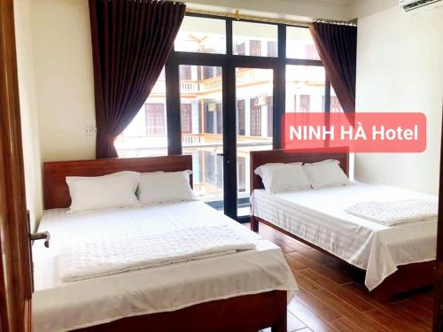 two beds in a room with a nini haa hotel at Khách Sạn Ninh Hà in Sầm Sơn