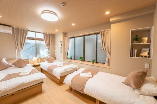 two beds in a room with two windows at New open 和風住宅 東中野駅 大久保駅徒歩圈内 新宿駅まで電車5分渋谷銀座東京近い 荷物預かります in Tokyo