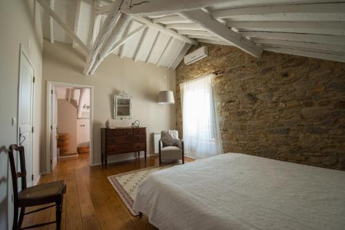 a bedroom with a bed and a stone wall at Quinta da Eira Velha in Aldeia do Mato
