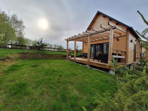 a small wooden house with a porch on a field at Domek Na Mazurach in Bogaczewo