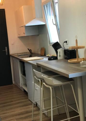 une cuisine avec un évier et un comptoir avec des tabourets dans l'établissement Studio cosy Beauvais, à Beauvais