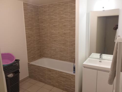 a bathroom with a bath tub and a sink at Chambre double 1 lit in Villepinte