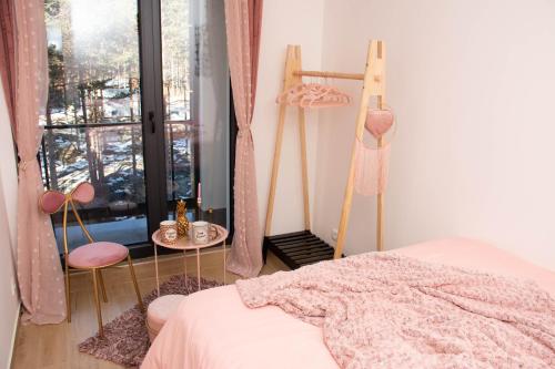 a bedroom with a bed and a window with pink chairs at MONA Apartman - Šumska Oaza in Divčibare
