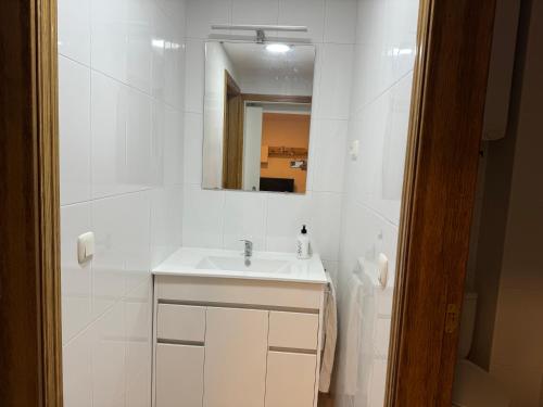 a white bathroom with a sink and a mirror at apartamento luanco playa in Luanco