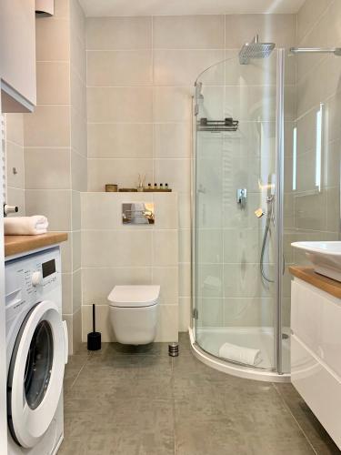 a bathroom with a shower and a toilet and a sink at REMAR - Apartamentai prie Necko Ežero in Augustów