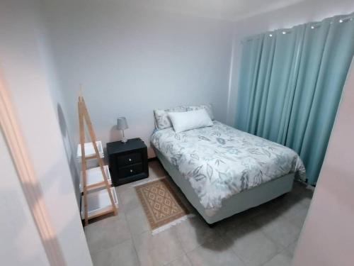 um quarto com uma cama com cortinas azuis e uma escada em Seashell Haven Hideout em Hentiesbaai