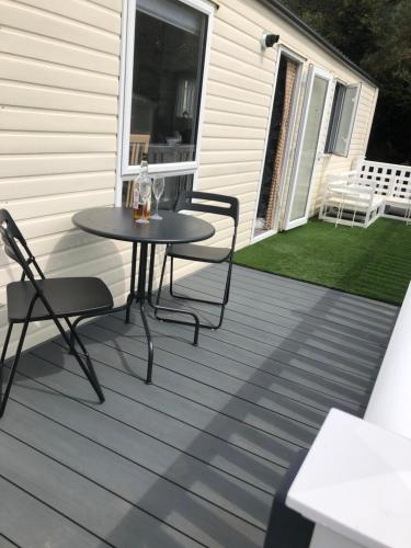 a patio with a table and chairs on a house at Seabreeze, Utopia, Shorefield Country Park, Milford on Sea, Shorefield Road, SO41 0LH, United Kingdom in Milford on Sea