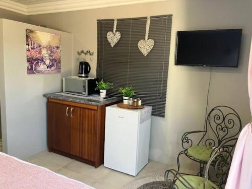a room with a kitchen with a microwave and a television at Stellies Accommodation - Room 2 in Keetmanshoop