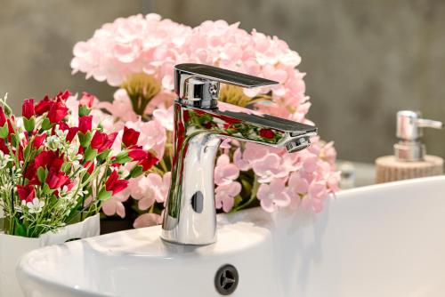 a bathroom sink with a faucet and pink flowers at ARI Yellow Apartment - Panoramic View in Arad