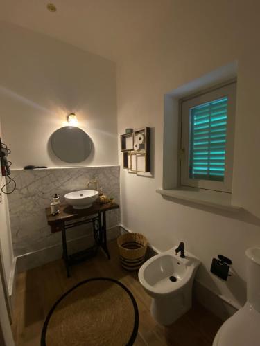a bathroom with a sink and a toilet and a mirror at Donna Carmela in Porticello