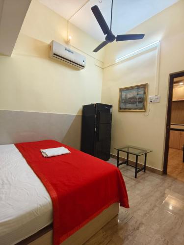 a bedroom with a bed with a red blanket and a fan at Shraddha hospitality in Calangute