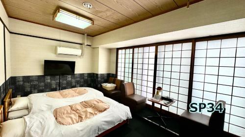 a bedroom with a bed and a chair and a window at Yufuin Akarinoyado in Yufuin