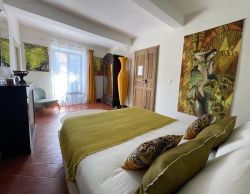 a bedroom with a bed with a painting on the wall at L'oiseau Bleu suite MERLE BLEU in Roubia