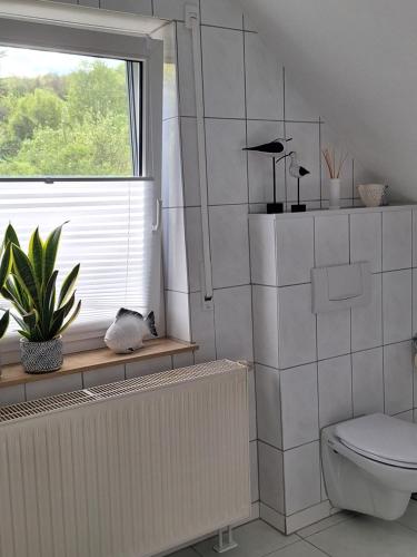 a bathroom with a toilet and a window and a plant at Ferienwohnung An der Karlskuppe in Eisenach