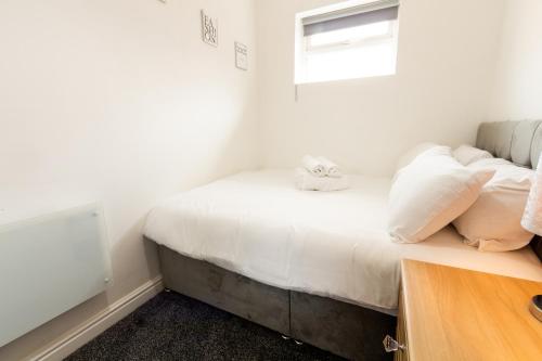 um quarto com uma cama com lençóis brancos e almofadas em Cosy & Compact Apartment in Swinton em Manchester