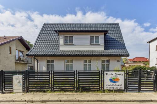 uma casa atrás de uma cerca com um sinal de sondagem em Dwie Sowy by Baltic Home em Międzyzdroje