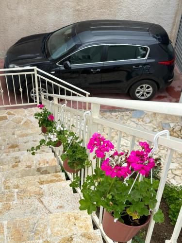 une voiture noire garée à côté d'une clôture avec des fleurs dans l'établissement Mediterranean Villa Old Town, à Vlorë