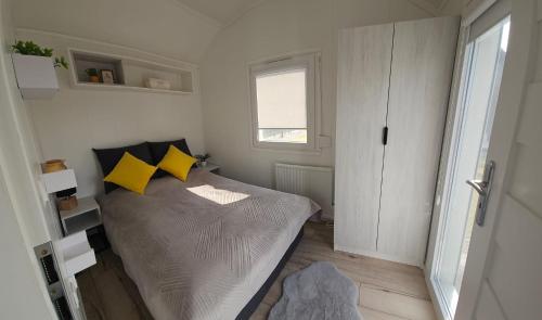 Dormitorio pequeño con cama con almohadas amarillas en Sosnowe Zacisze, en Rydzewo