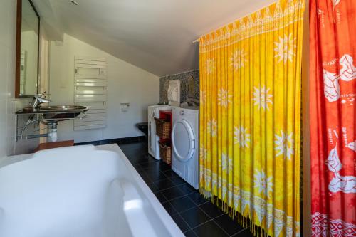 une salle de bain avec une machine à laver et un rideau de douche jaune dans l'établissement Villa l'Accalmie - 10 pers - Entre lac et mer, à Seignosse