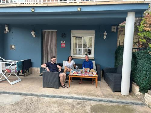 three people sitting around a table in front of a house at Pensión Jauja in Alesanco