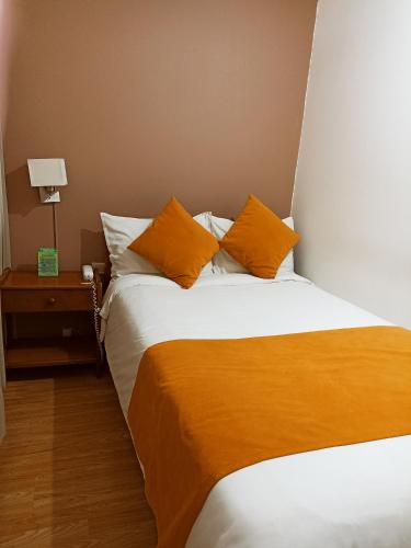 a bedroom with a large bed with orange pillows at Hotel Tuvalu in Paipa