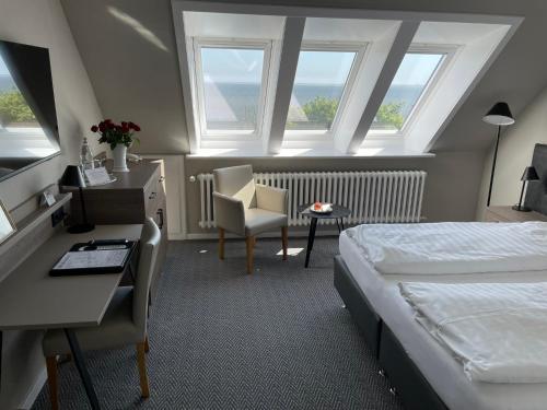 een hotelkamer met een bed, een bureau en een raam bij Kurhaus Hotel in Wyk auf Föhr