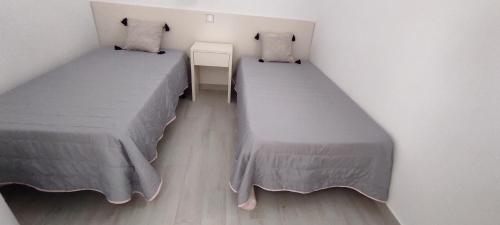Duas camas num pequeno quarto com duas saias. em Casinha do Mar em Carvide