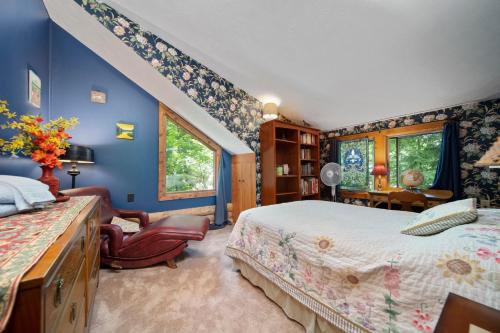 1 dormitorio con paredes azules, 1 cama y 1 silla en Beautiful Log Cabin Wooded Lake Access Interlochen Arts Academy, en Interlochen