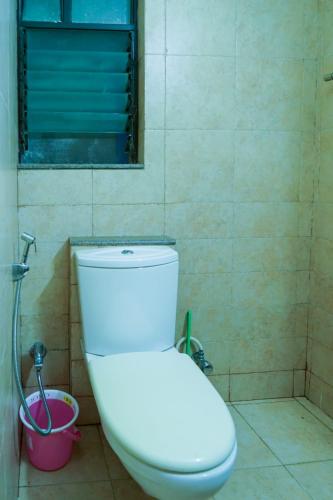a bathroom with a toilet and a window and a bucket at AP's Castle Stay in Kharadi