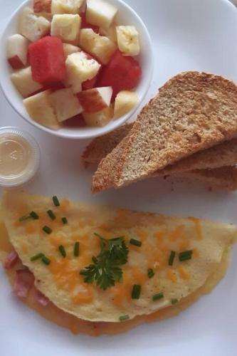 a plate of food with a bowl of fruit and a sandwich at Gated Riverside Studio Apartment in San Juan