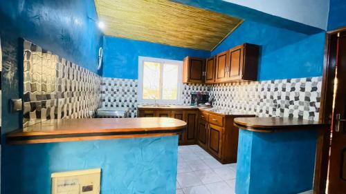 una grande cucina con pareti blu e armadi in legno di Residence les Berniers a Nianing