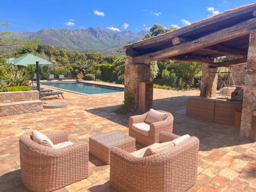 une terrasse avec des chaises en osier et une piscine dans l'établissement Domaine du Reginu, à Santa-Reparata-di-Balagna
