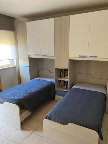 Duas camas num quarto com armários brancos em Villetta Susy em Valrovina