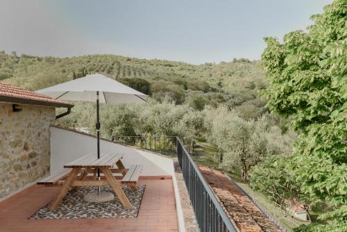 a wooden picnic table with an umbrella on a balcony at Agriturismo Il Mulino delle canutole in Magione