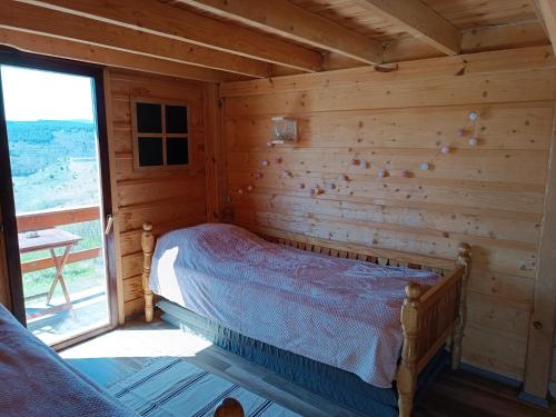 una camera con un letto in una baita di tronchi di Avlija Biberović a Sjenica
