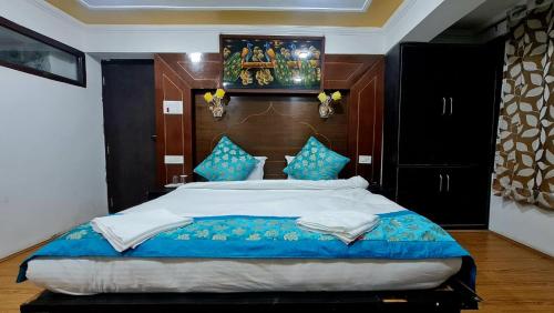 a bedroom with a large bed with blue pillows at HOTEL D INDIAN KARGIL in Kargil
