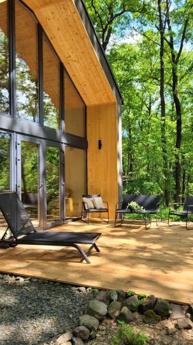 a house with a wooden deck with chairs and benches at Bérc Kabin Kismaros in Kismaros