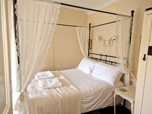 a bedroom with a canopy bed with white sheets and pillows at Brynifor Llangrannog in Llwyn-Dafydd