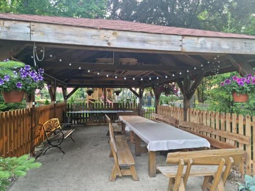 a wooden pavilion with tables and benches and flowers at Pałac Ogartowo in Połczyn-Zdrój