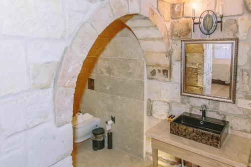 a stone bathroom with a sink and a mirror at Panoramic Cave Hotel in Goreme