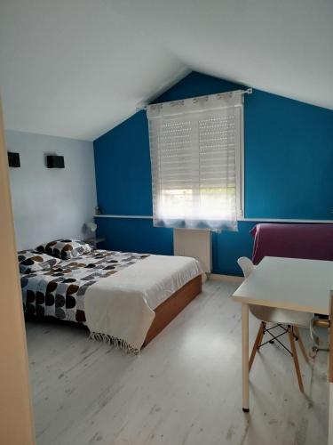 a bedroom with a bed and a blue wall at Le champ Vert in Chamblanc