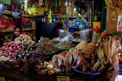 a man standing in a market with a pile of food at NJ House in Tangalle