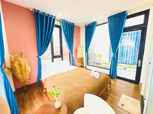 1 dormitorio con 1 cama grande con cortinas azules en Be Youth Villa Đà Lạt en Dalat